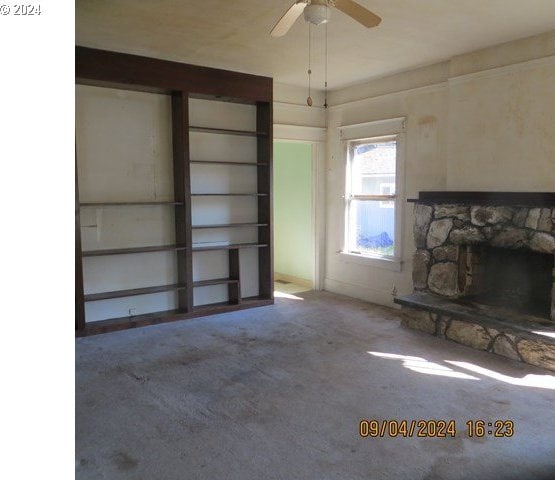 unfurnished living room featuring carpet, ceiling fan, and a fireplace