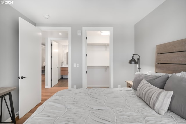 bedroom featuring a spacious closet, wood-type flooring, and a closet