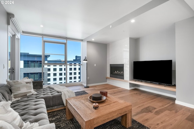 living room featuring hardwood / wood-style flooring, a large fireplace, and a wall of windows