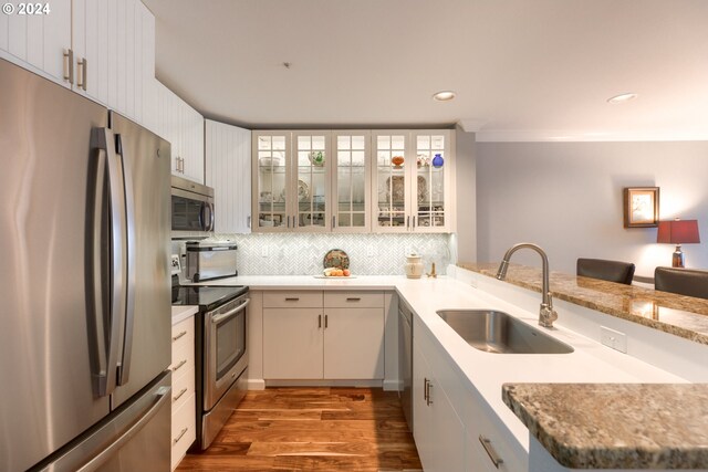 kitchen with kitchen peninsula, sink, white cabinets, and stainless steel appliances