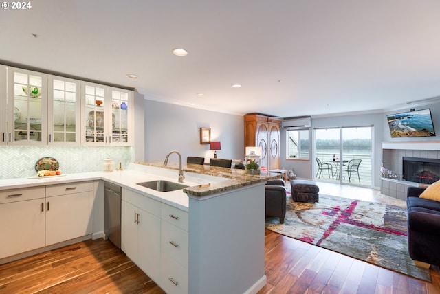 kitchen featuring kitchen peninsula, hardwood / wood-style floors, white cabinets, and a tiled fireplace