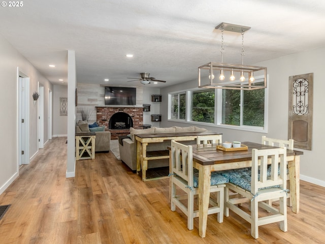 15836 SW Division St, Sherwood, OR 97140 - dining area featuring light wood-style flooring, ceiling fan, a brick fireplace, baseboards, and recessed lighting