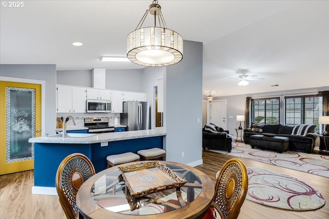 dining space with ceiling fan, light wood-type flooring, lofted ceiling, and sink