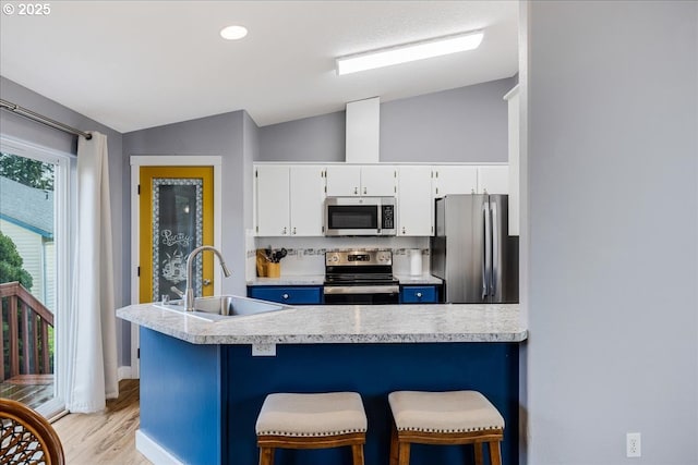 kitchen with white cabinets, sink, appliances with stainless steel finishes, and vaulted ceiling