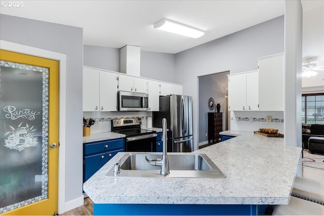 kitchen with sink, a kitchen breakfast bar, blue cabinets, white cabinets, and appliances with stainless steel finishes