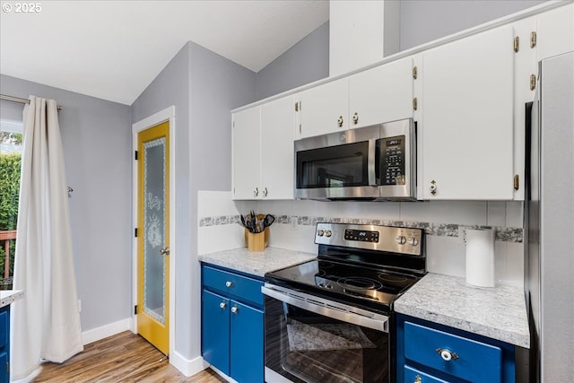 kitchen with blue cabinetry, stainless steel appliances, and white cabinetry