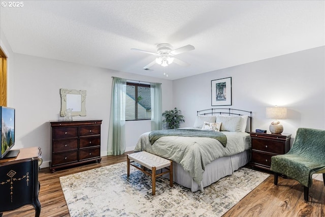 bedroom featuring ceiling fan, wood-type flooring, and a textured ceiling