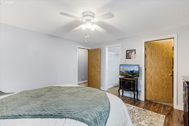 bedroom with a textured ceiling, ceiling fan, and dark wood-type flooring