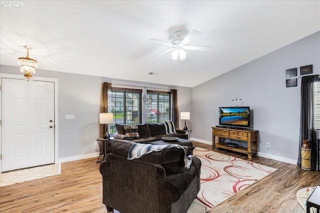 living room featuring ceiling fan with notable chandelier, light hardwood / wood-style flooring, and lofted ceiling