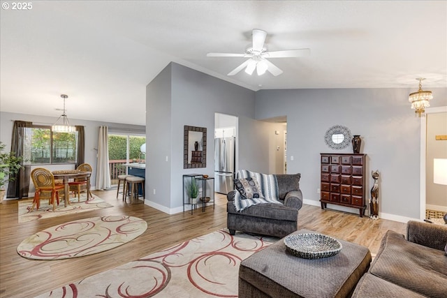 living room featuring light hardwood / wood-style flooring, ceiling fan with notable chandelier, and vaulted ceiling