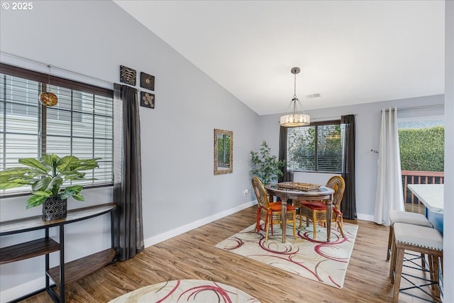 dining room featuring light hardwood / wood-style flooring, a chandelier, and vaulted ceiling