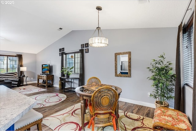 dining room with hardwood / wood-style flooring and vaulted ceiling