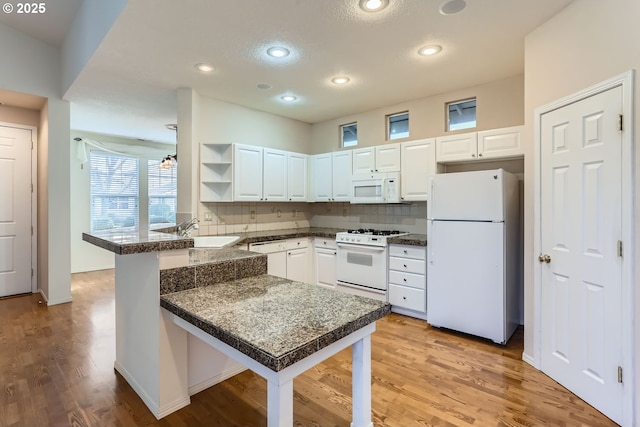 kitchen featuring white appliances, backsplash, sink, kitchen peninsula, and white cabinetry