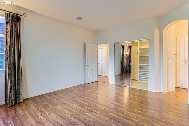 unfurnished bedroom with a walk in closet, light hardwood / wood-style flooring, and a closet