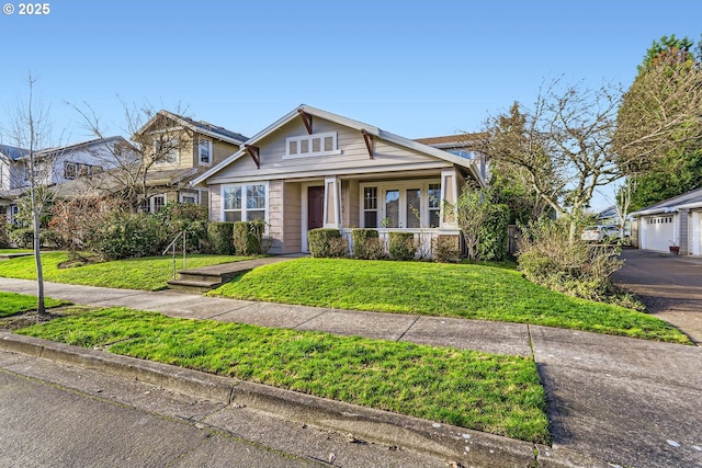 view of front of home with covered porch, a garage, and a front lawn