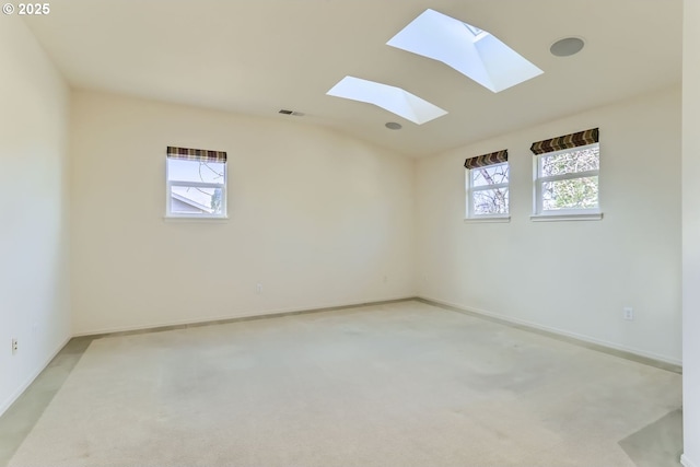 carpeted spare room with a wealth of natural light and vaulted ceiling with skylight