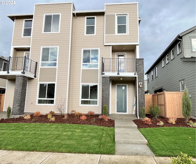 view of front facade featuring a front yard and a balcony