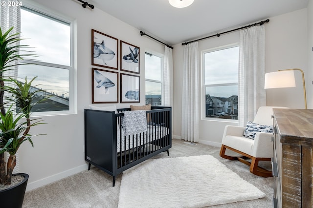 bedroom with multiple windows, light carpet, and a crib