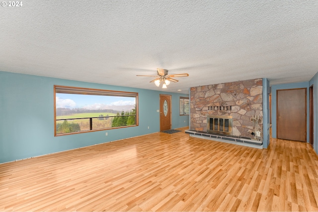 386 Longview Dr, Elkton, OR 97436 - unfurnished living room featuring wood finished floors, ceiling fan, a textured ceiling, and a stone fireplace