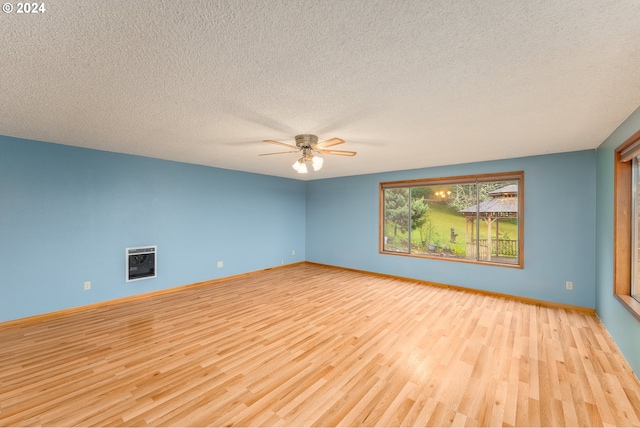 unfurnished room featuring heating unit, a textured ceiling, and light wood-type flooring