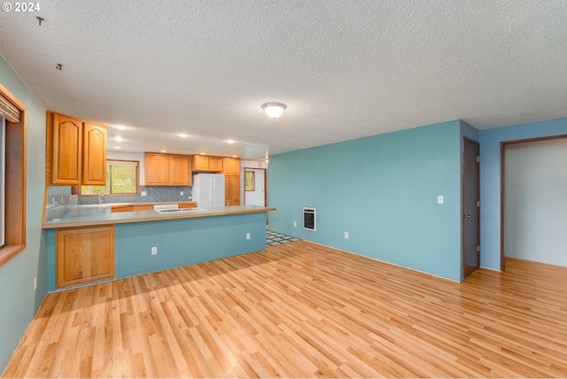 386 Longview Dr, Elkton, OR 97436 - kitchen with a peninsula, light wood-type flooring, a textured ceiling, freestanding refrigerator, and a sink