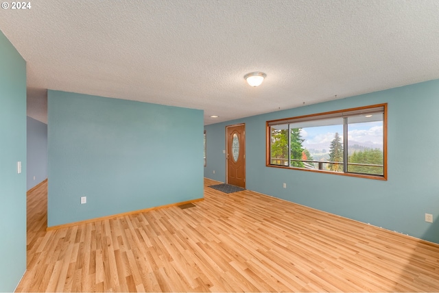 unfurnished room with a textured ceiling and light hardwood / wood-style flooring