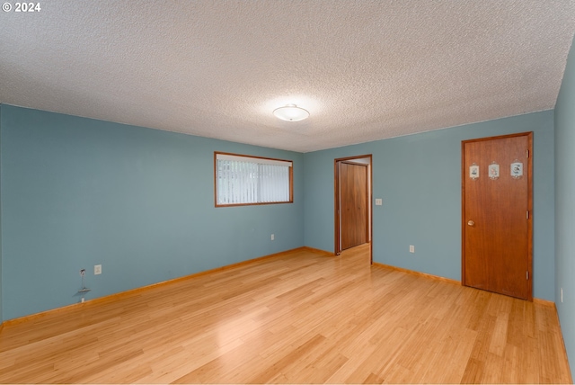 unfurnished room with light wood-type flooring and a textured ceiling