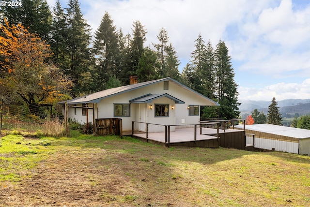 rear view of house with a yard and a deck with mountain view