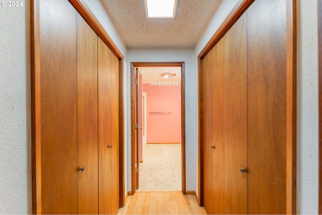 hallway featuring a textured ceiling and light hardwood / wood-style floors