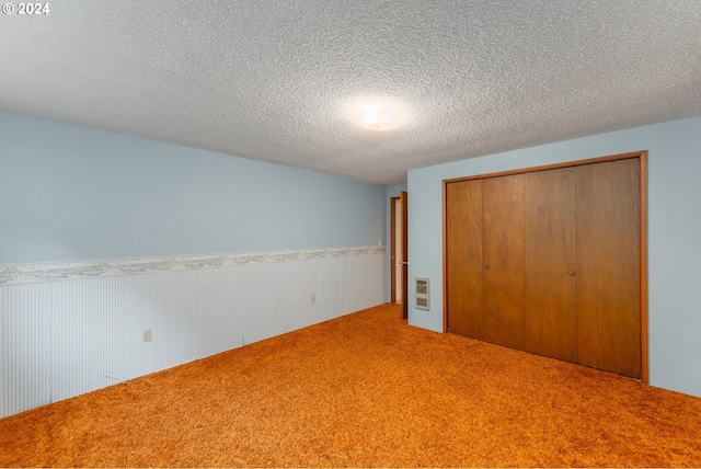 unfurnished bedroom featuring a textured ceiling, carpet floors, and a closet