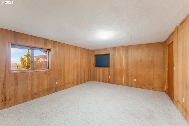 empty room with a textured ceiling and wood walls