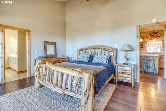 bedroom featuring hardwood / wood-style floors, a towering ceiling, and ensuite bath