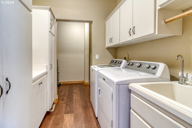 washroom with dark hardwood / wood-style floors, cabinets, sink, and washing machine and clothes dryer