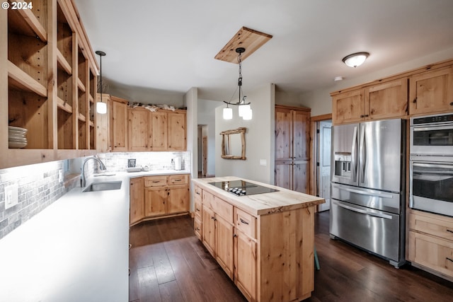 kitchen with appliances with stainless steel finishes, dark wood-type flooring, sink, a kitchen island, and hanging light fixtures