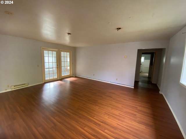 spare room with dark wood-type flooring and a baseboard heating unit