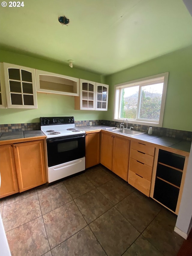 kitchen featuring tile counters, sink, dark tile patterned floors, and white range with electric cooktop