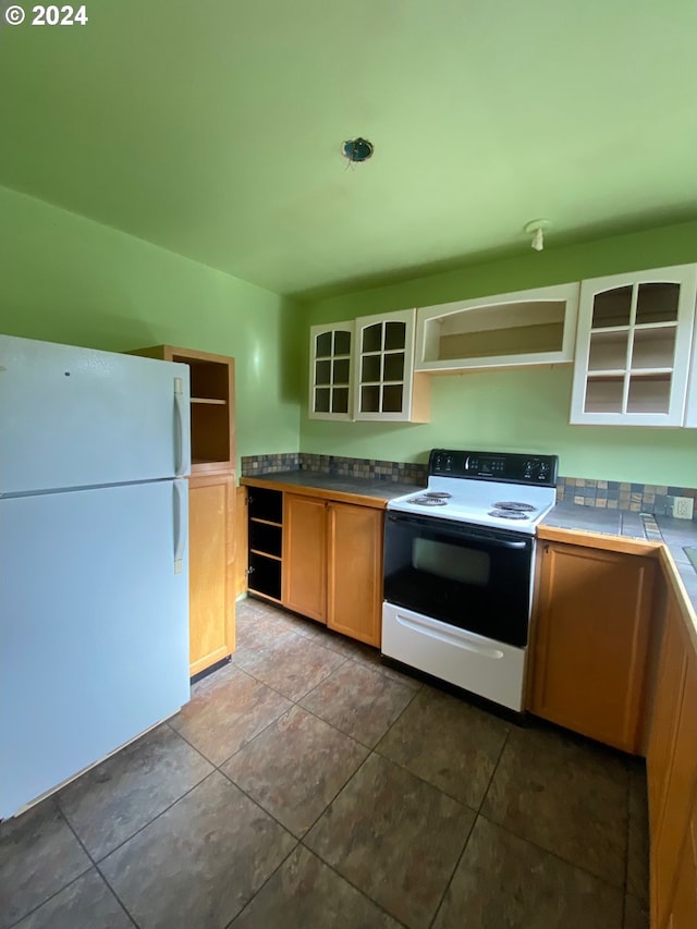 kitchen with tile countertops, dark tile patterned flooring, and white appliances