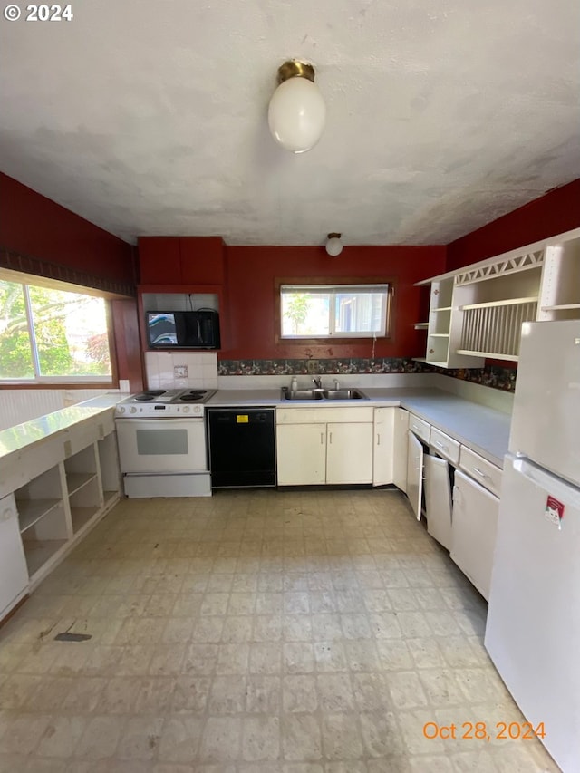 kitchen featuring black appliances, white cabinetry, a wealth of natural light, and sink