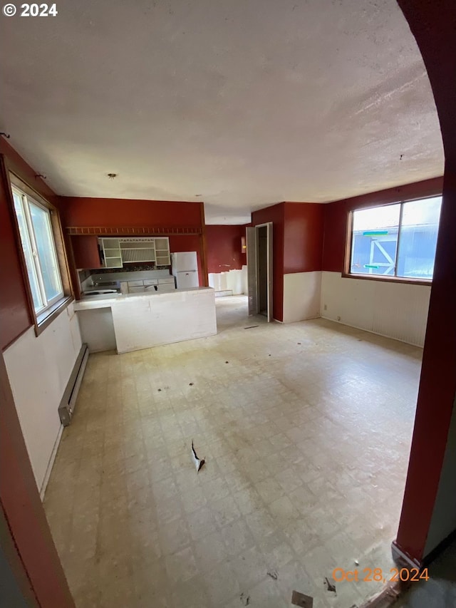 kitchen with kitchen peninsula, white fridge, and a baseboard heating unit