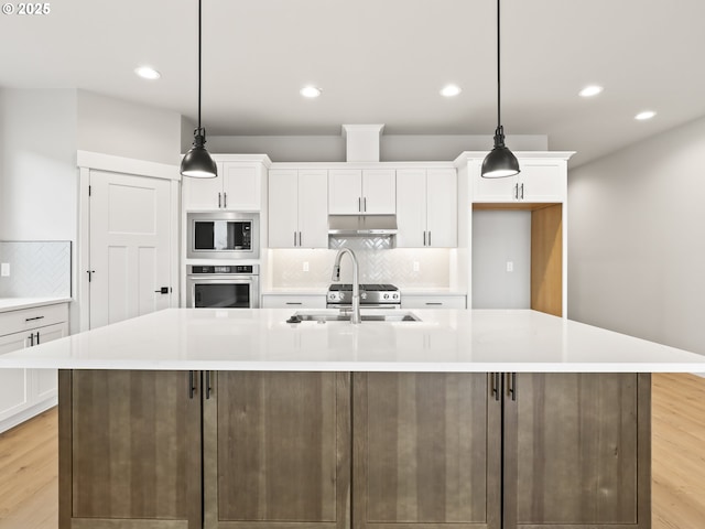 2891 NE Currin Creek Dr, Estacada, OR 97023 - kitchen featuring under cabinet range hood, stainless steel appliances, white cabinetry, and a sink
