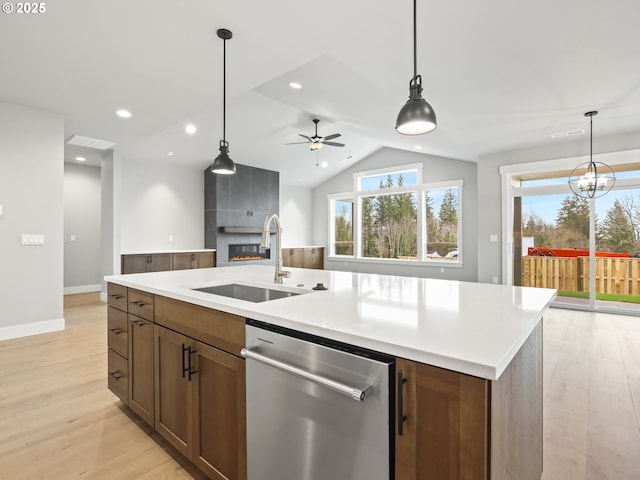2891 NE Currin Creek Dr, Estacada, OR 97023 - kitchen with ceiling fan with notable chandelier, a sink, a tiled fireplace, light wood-type flooring, and stainless steel dishwasher