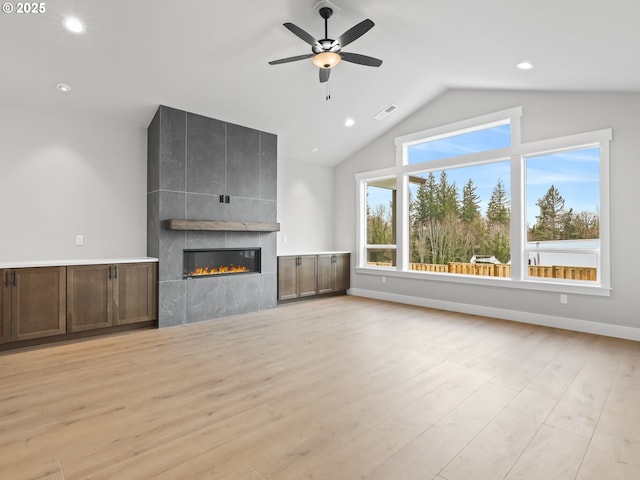 2891 NE Currin Creek Dr, Estacada, OR 97023 - unfurnished living room with a ceiling fan, a tiled fireplace, visible vents, lofted ceiling, and recessed lighting