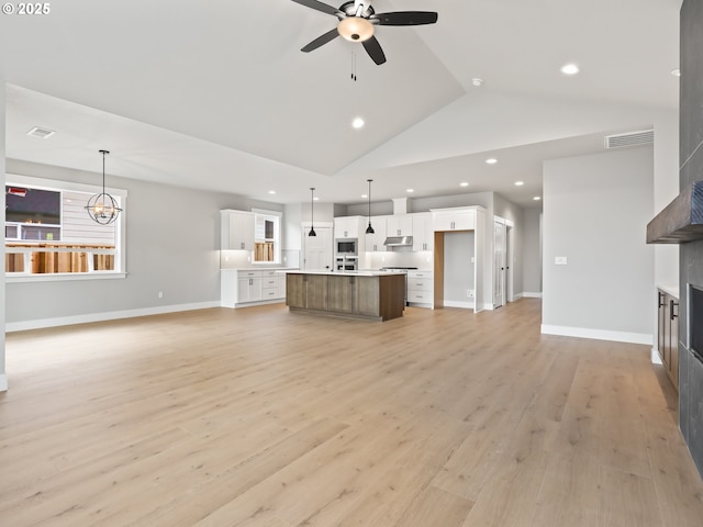 2891 NE Currin Creek Dr, Estacada, OR 97023 - unfurnished living room with light wood-type flooring, lofted ceiling, ceiling fan with notable chandelier, and a fireplace
