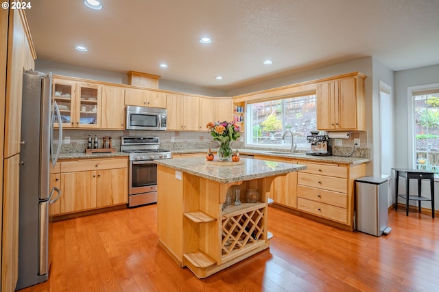 kitchen featuring sink, stainless steel appliances, a center island, and light wood-type flooring