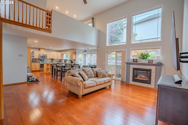 living room featuring light hardwood / wood-style flooring, a fireplace, and a high ceiling