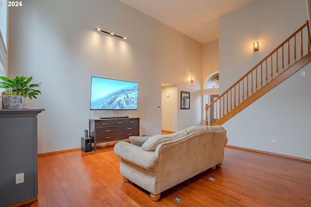 living room with light hardwood / wood-style floors and a high ceiling