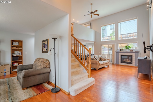 living room featuring a towering ceiling, light hardwood / wood-style flooring, and ceiling fan