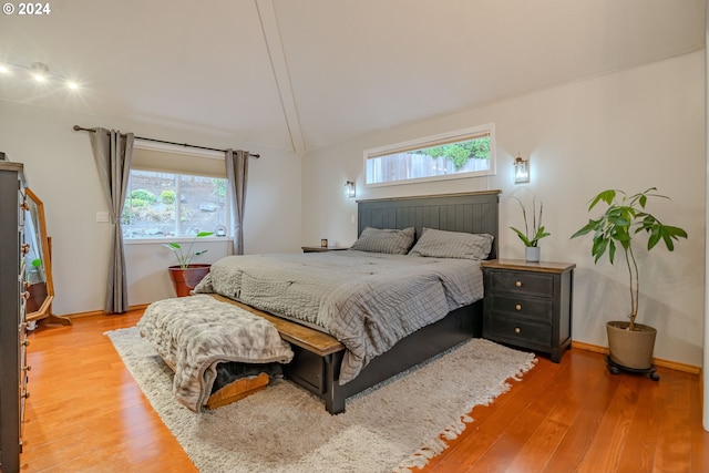 bedroom featuring vaulted ceiling, multiple windows, and hardwood / wood-style flooring