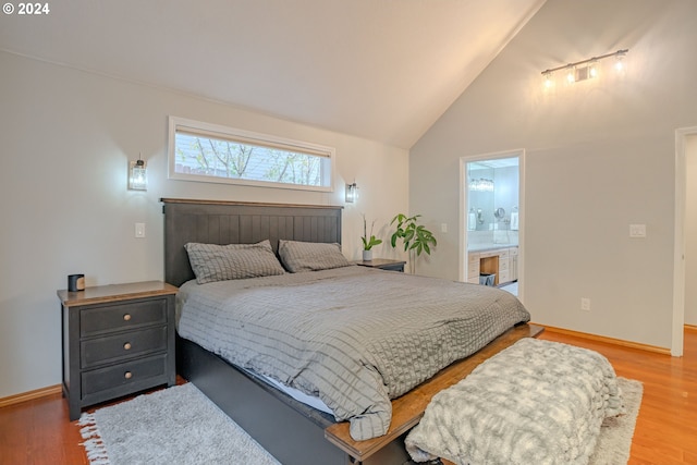 bedroom with vaulted ceiling, ensuite bathroom, and hardwood / wood-style flooring