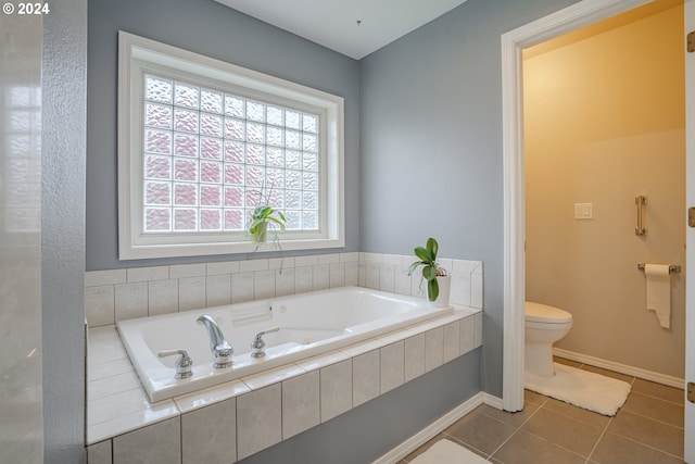 bathroom with toilet, a relaxing tiled tub, and tile patterned flooring